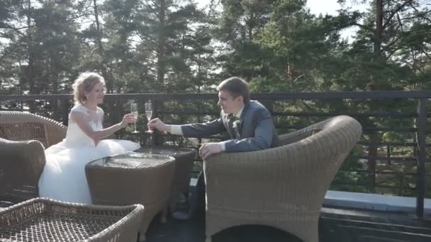 The bride and groom drinking champagne sitting on the verandah, summer cafe, Steadicam — Stock Video