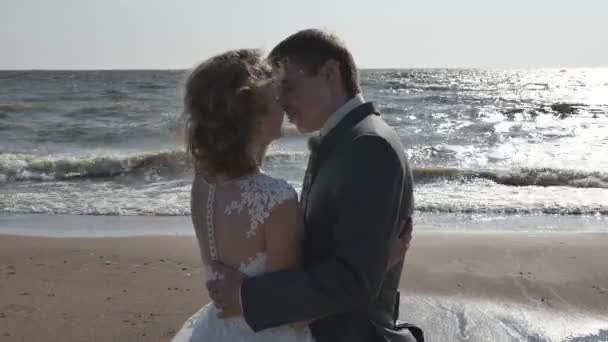 Par som står på stranden kyssar, back-light, kamerarörelser — Stockvideo