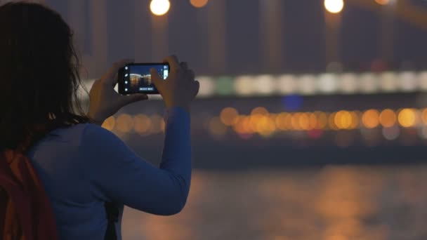 Het meisje met de telefoon kijkt naar de brug van Perth, de groot, de rivier de Neva — Stockvideo