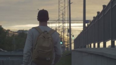 Genç bir adam şehirde elinde kahvesiyle bir kaykay sürmek