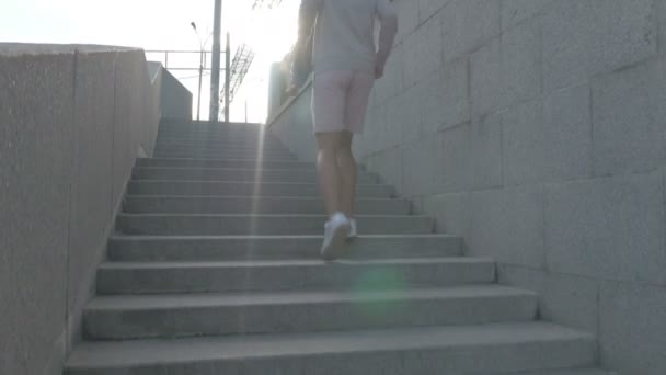 The skateboarder goes up the stairs on the street with a skateboard in hand. — Stock Video