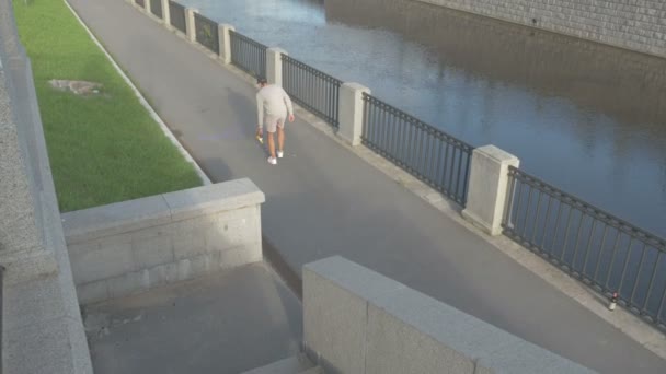 The skateboarder goes up the stairs on the street with a skateboard in hand. — Stock Video