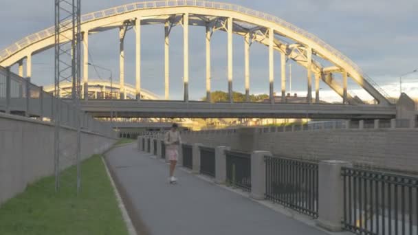 Jeune homme en ville sur une planche à roulettes avec une tablette à la main en été — Video