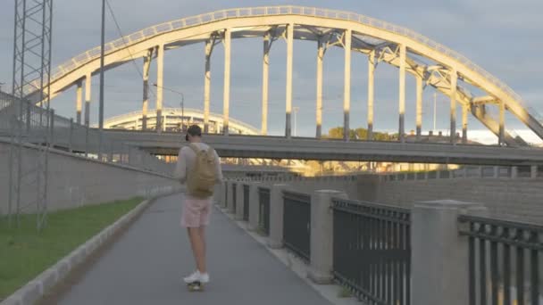 Молодой парень в городе на скейтборде с табличкой в руке летом — стоковое видео