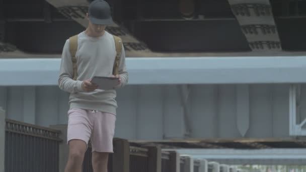 Pemuda di kota pada skateboard dengan tablet di tangan di musim panas — Stok Video