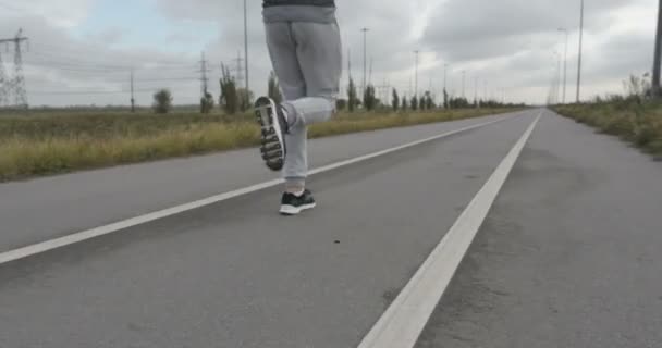 Człowiek w trampki działa na asfalt poza miastem. — Wideo stockowe