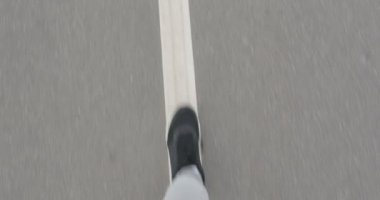 Şehir dışında asfalt üzerinde bir erkek spor ayakkabı içinde çalışır.