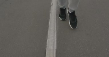 Şehir dışında asfalt üzerinde bir erkek spor ayakkabı içinde çalışır.