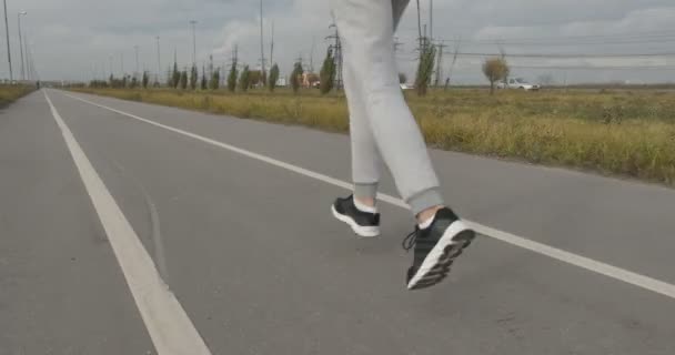 Человек в кроссовках бежит по асфальту за городом . — стоковое видео