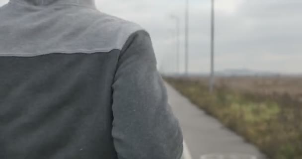 Un uomo in scarpe da ginnastica corre sull'asfalto fuori città . — Video Stock