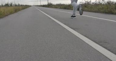 Şehir dışında asfalt üzerinde bir erkek spor ayakkabı içinde çalışır.
