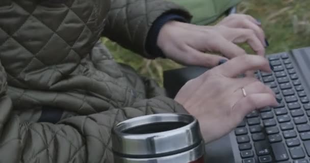 Junge brünette Studentin arbeitet in der Natur am Laptop. schöner Herbsttag und Frau genießt es, während sie Laptop benutzt. — Stockvideo