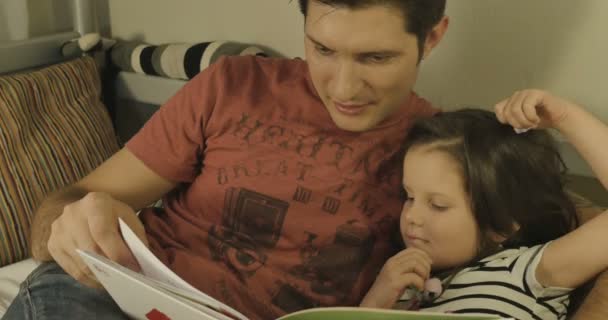 Un padre y una hija pasan tiempo juntos leyendo un libro — Vídeos de Stock