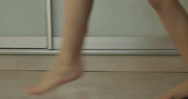 子供が床に沿って歩き、ベッドに横たわる — ストック動画