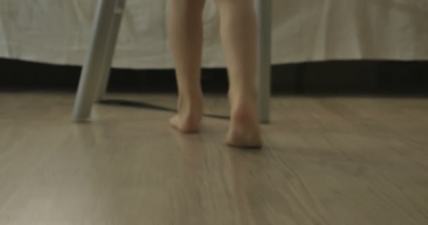 Ένα παιδί περπατάει στο πάτωμα και κάθεται στο κρεβάτι — Αρχείο Βίντεο
