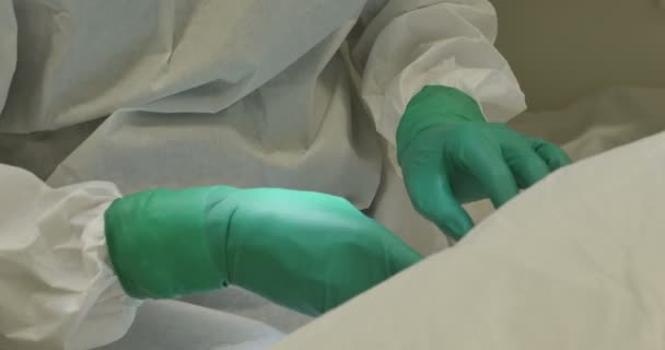 Gros plan mains portant des gants chirurgicaux équipe opératoire vêtements de protection effectuant la chirurgie à l'aide d'équipement stérilisé — Video