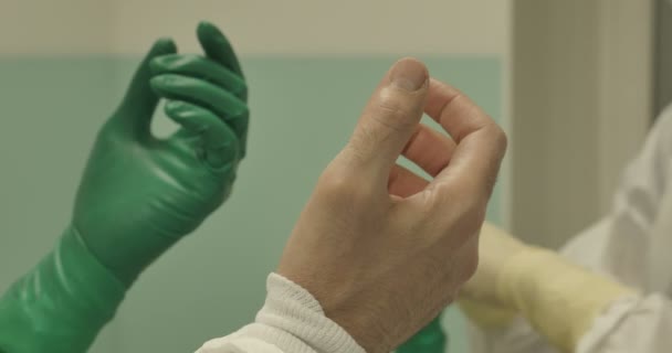 Hände aus nächster Nähe mit OP-Handschuhen und Schutzkleidung für das Operationsteam, das mit sterilisierten Geräten operiert — Stockvideo