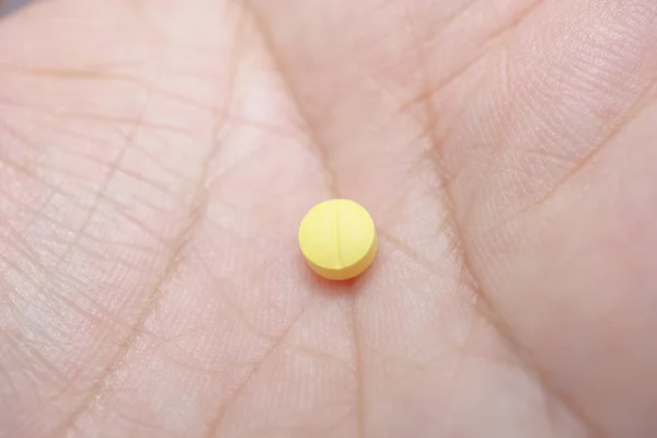 Желтая таблетка на пальце — стоковое фото