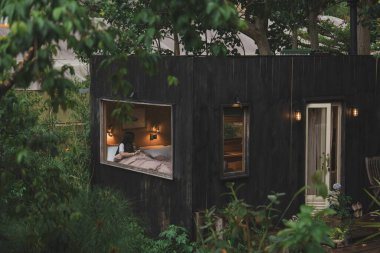 Yatakta, karanlık bir kulübede, dış yüzeyi yemyeşil bir bitki örtüsüyle çevrili bir kadın.