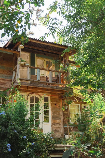 Yeşilliklerle çevrili ahşap kulübe. İki katlı konutta bir balkon var.