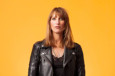 Sarı bir fonun önünde siyah deri ceket giyen güzel bir kadının portresi.