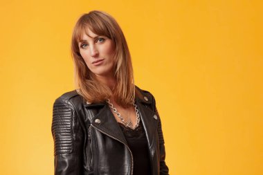 Sarı bir fonun önünde siyah deri ceket giyen güzel bir kadının portresi.