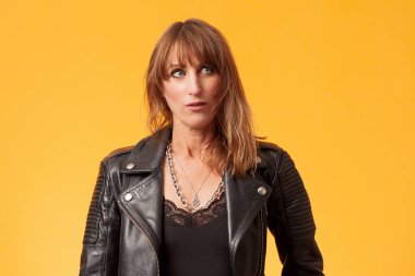 Sarı bir fonun önünde siyah deri ceket giyen güzel bir kadının portresi.