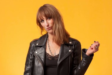 Sarı bir fonun önünde siyah deri ceket giyen güzel bir kadının portresi.