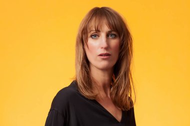 Sarı arka planda siyah bluz giyen çekici bir kadının portresi.