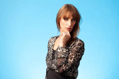 Mavi arka planda leopar desenli bluz giyen güzel esmer bir kadının portresi.