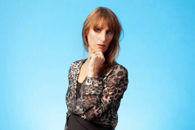 Mavi arka planda leopar desenli bluz giyen güzel esmer bir kadının portresi.