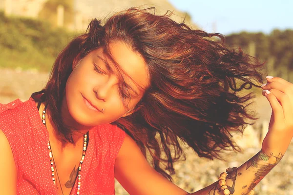 The girl with a tattoo on the coast close-up with developing hair in the wind — Stock Photo, Image