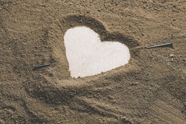 Silhouette of heart drawn in the sand clay clipart