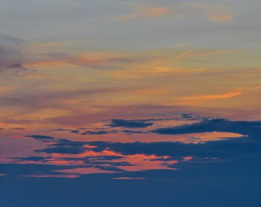 Glowing evening sky with pastel colors and magical sunset light painting the clouds, creating a serene and poetic mood.