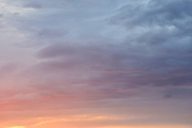 Günbatımı gökyüzünü sıcak, parlak pastel tonlarda altın ve pembeyle doldurur. Huzurlu bir ufukta süzülen bulutları hafifçe aydınlatır..