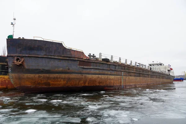 An old rusty motor ship is awaiting disposal. Wintering ships on a frozen river in their port. Volgograd. Russia