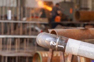 Pipeline. Electric gas welding. Butt weld seam of welding the pipeline DN50 to the bend and the pipe against the background of sparks from stripping the seam. Oil and gas pipeline.  