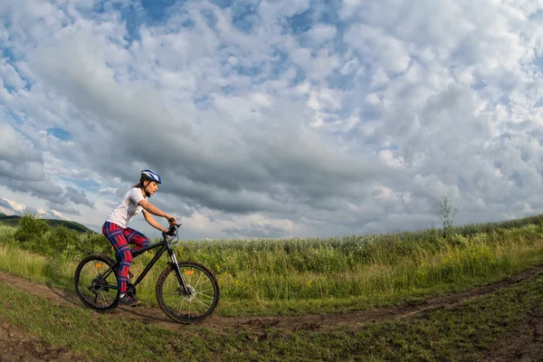 Giovane donna in sella alla sua bicicletta su un sentiero rurale — Foto Stock