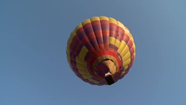 Красно-желтый шар, летящий в безоблачном небе — стоковое видео