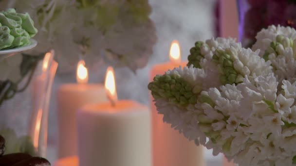Közeli kép a gyertyát, a háttérben virágok — Stock videók