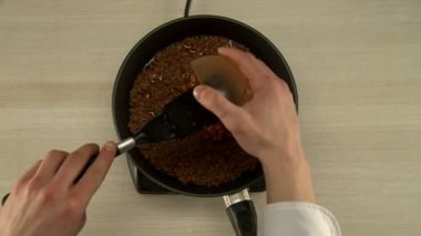 Pişirme sırasında fasulye ve eti karıştırır.