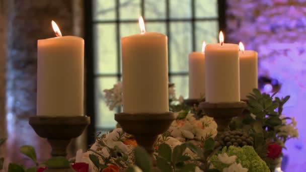 Зажженные свечи и цветы на фоне окна — стоковое видео