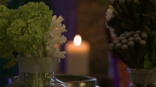 Свежие срезанные цветы на фоне зажженной свечи — стоковое видео
