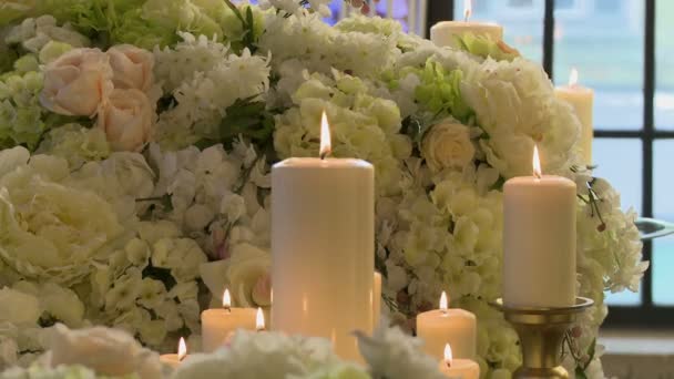 Velas iluminadas no fundo de flores brancas — Vídeo de Stock