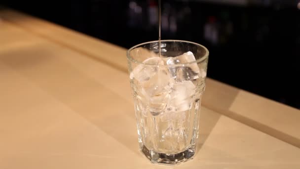 View of bartender pours liquor into glass with ice — Stock Video