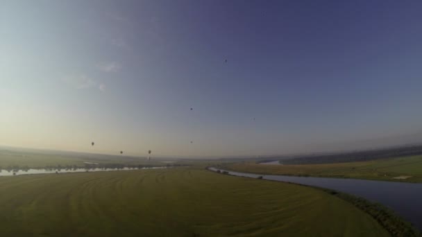 Vista superior de balões de ar voar sobre o campo e rio — Vídeo de Stock