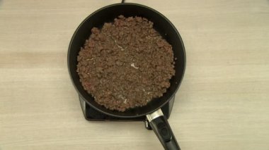 Pişirme sırasında fasulye ve eti karıştırır.