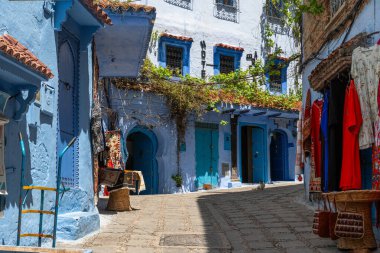 Geleneksel Fas giysileri ve giysileri Şef Medine 'de tipik bir mavi sokak boyunca sergilenmektedir.