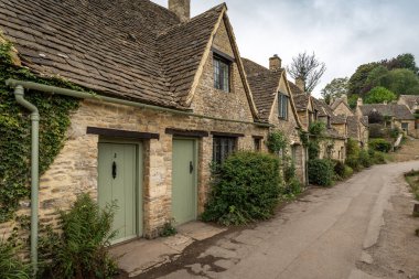 Cotswolds 'un en güzel köylerinden biri olan Bibury' deki resimli Arlington Row kulübeleri.