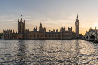 Londons 'un simgesi Big Ben ve Westminster Sarayı' nın gün batımında Thames Nehri 'ni geçen Westminster Köprüsü' nün manzarası.